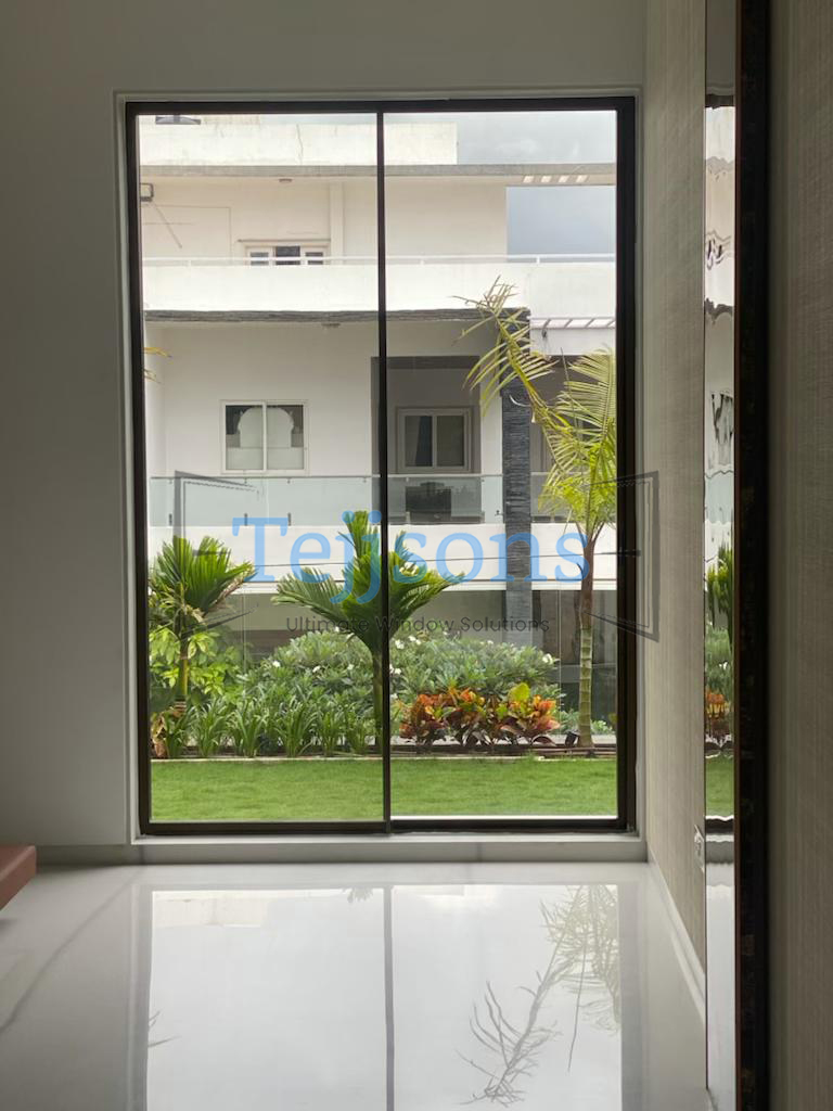 Large minimalist window framing a lush garden courtyard